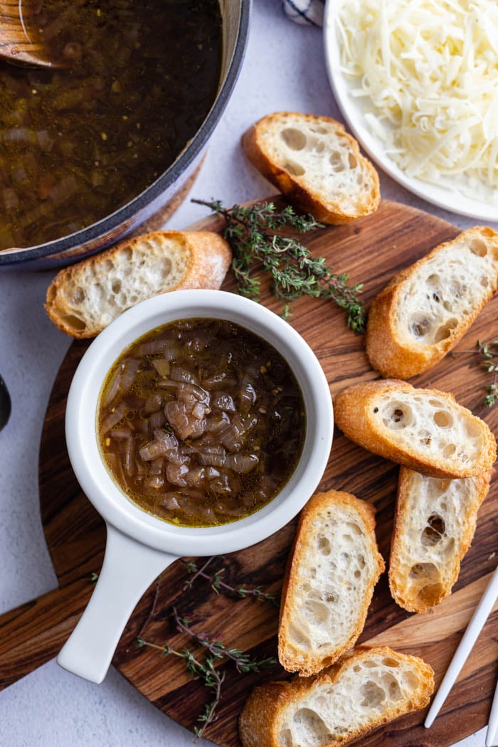 french onion soup in a white bowl with toasted bread around it