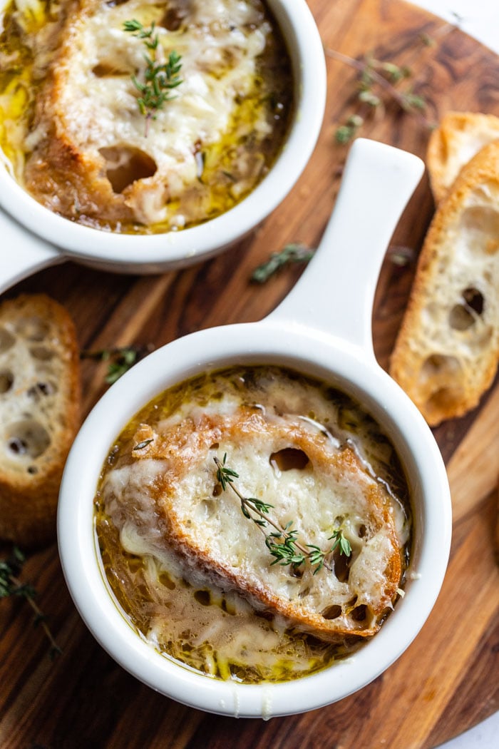 several white bowls of french onion soup with bread and cheese on top