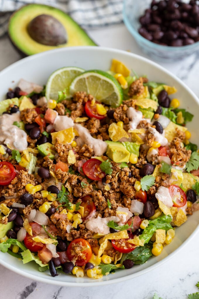 vegetarian taco salad loaded with lettuce, tomato, avocado, walnut meat, and a cream sauce